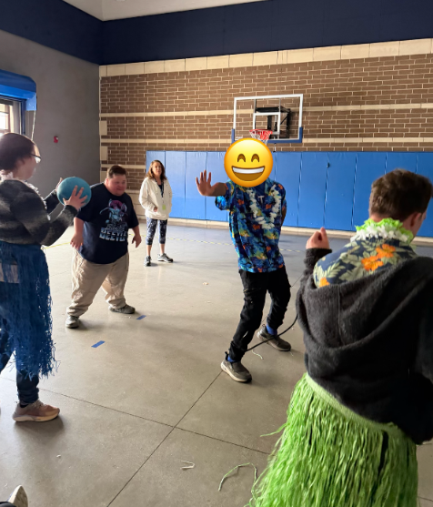 Students in hawaiian shirts and grass skirts dancing