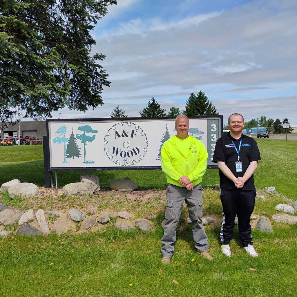 Two men standing in front of a business sign.