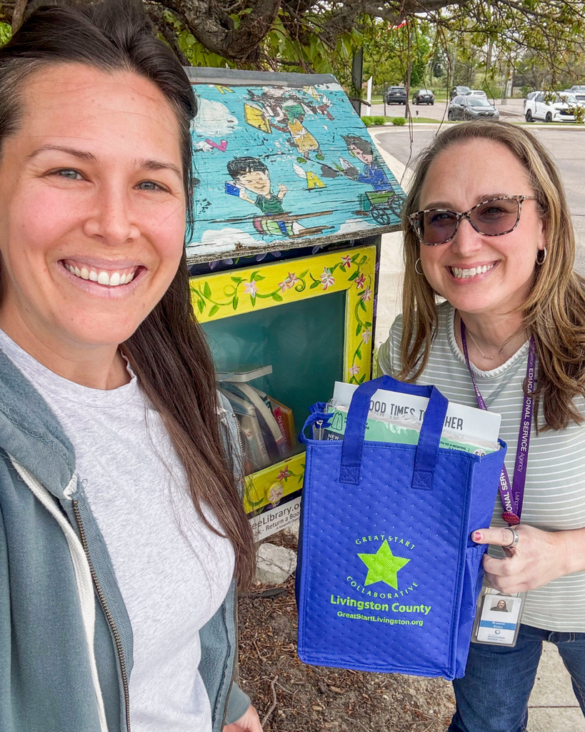 Two women standing in front of our Little Free Library