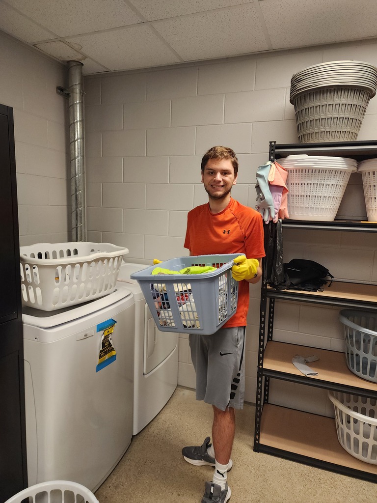 A male adult learner holding a laundry basket filled with clothes.
