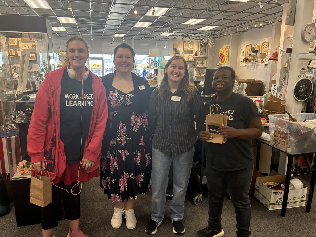 Two students smiling alongside staff at the LACASA Center donation collection site during a work-based learning experience.