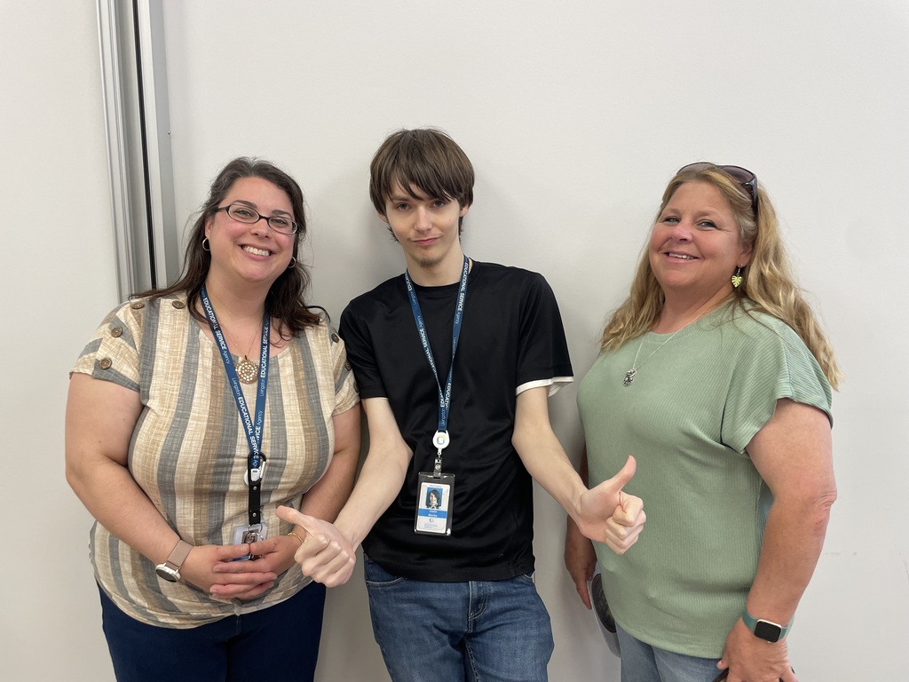 Two female teachers standing with a young male adult learner.