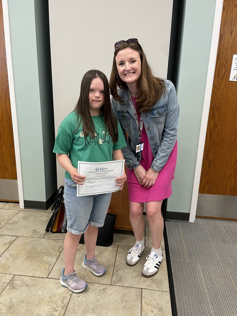 A young adult learner standing with her teacher.
