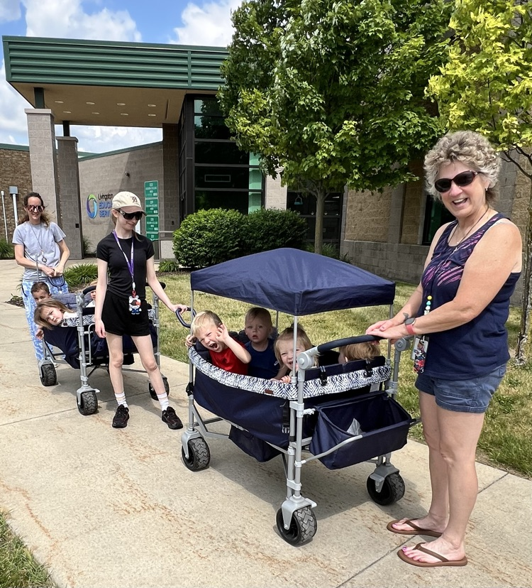 Three teachers pulling two wagons of little learners 