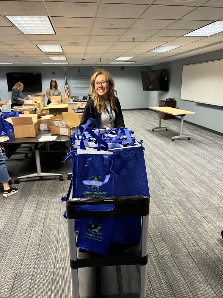 Woman with wheeled cart full of blue bags.