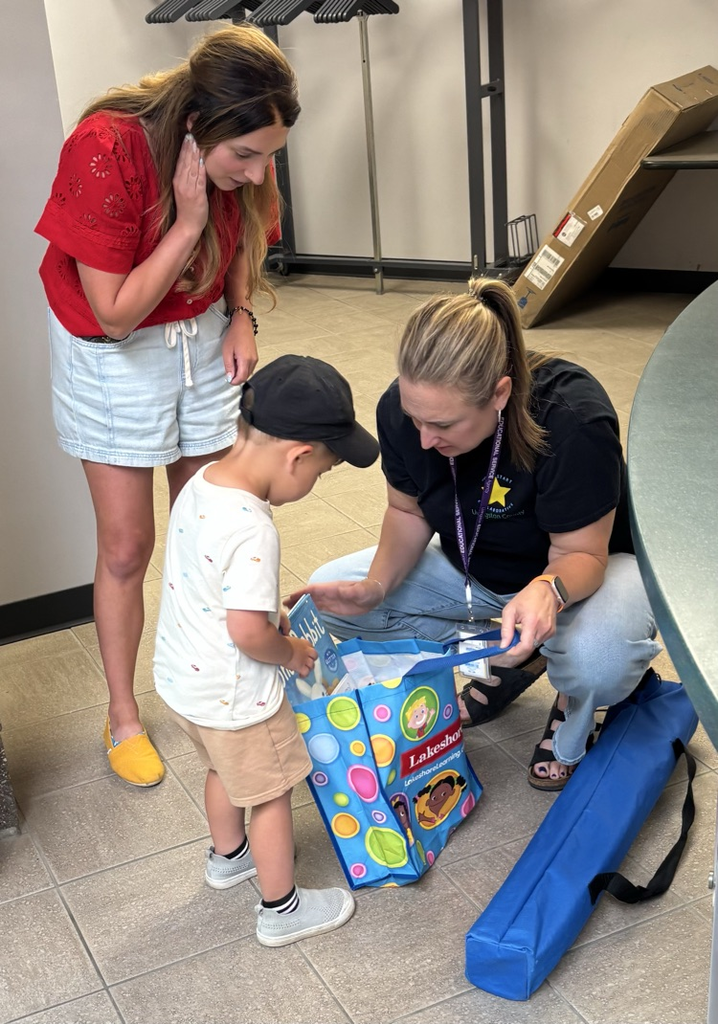 Young boy and his mom look into a gift bag held by another person.