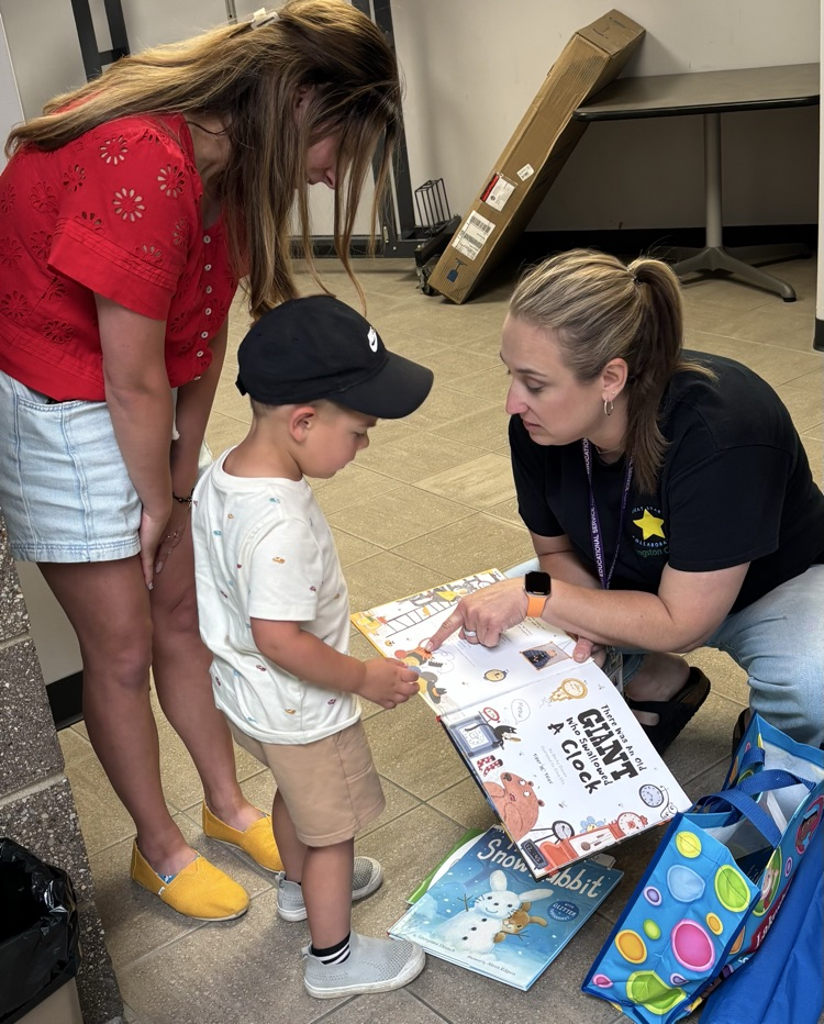 Young boy and his mom look at a book held by another woman.