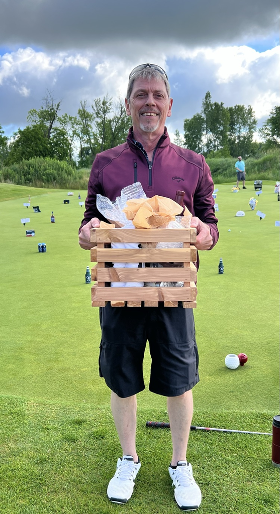 Adult Male holds a wooden box full of prizes. 