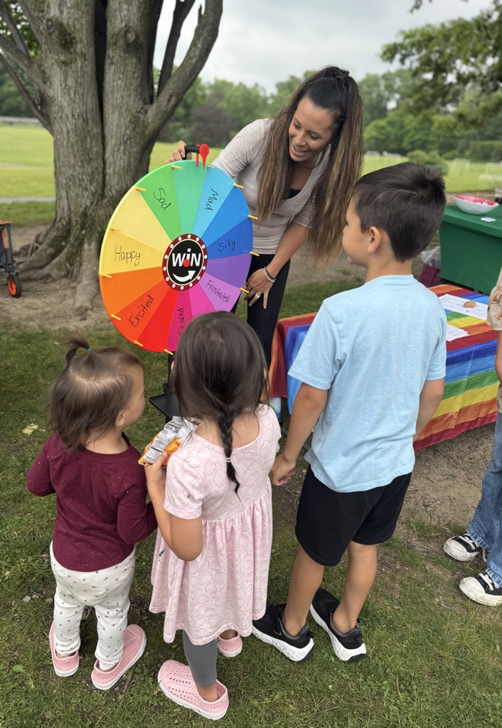 Small group of children taking turns spinning a colorful wheel.