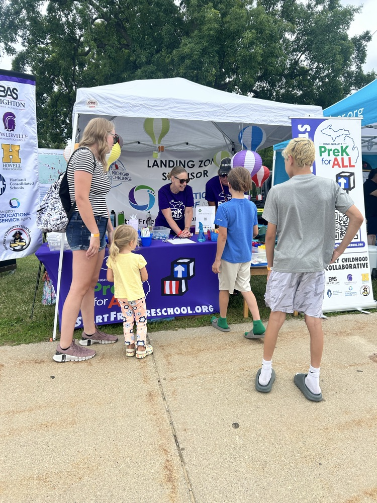 Tent with people in matching purple shirts and families gathered outside to see what they have.