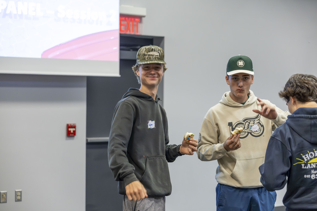 Two teenage boys standing side-by-side, smiling and holding ice cream treats.