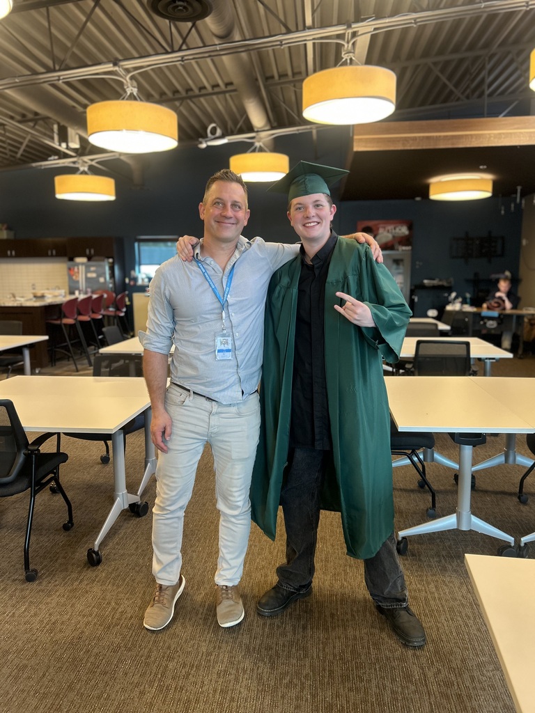 Young man in his cap and ground standing with his male teacher.