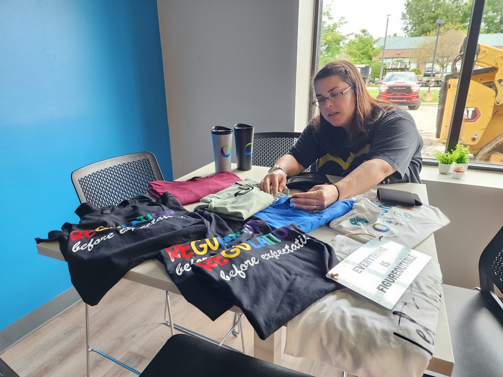 One female sitting, looking through a tables with shirts.