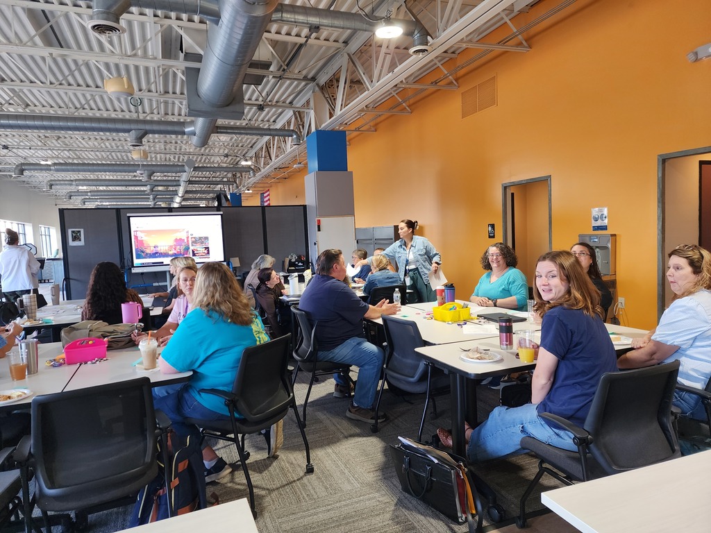 A group of female teachers sitting at tables conversing.
