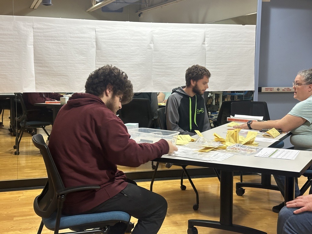 PREP sudents working on assembly tasks with a Job Coach at a classroom table.