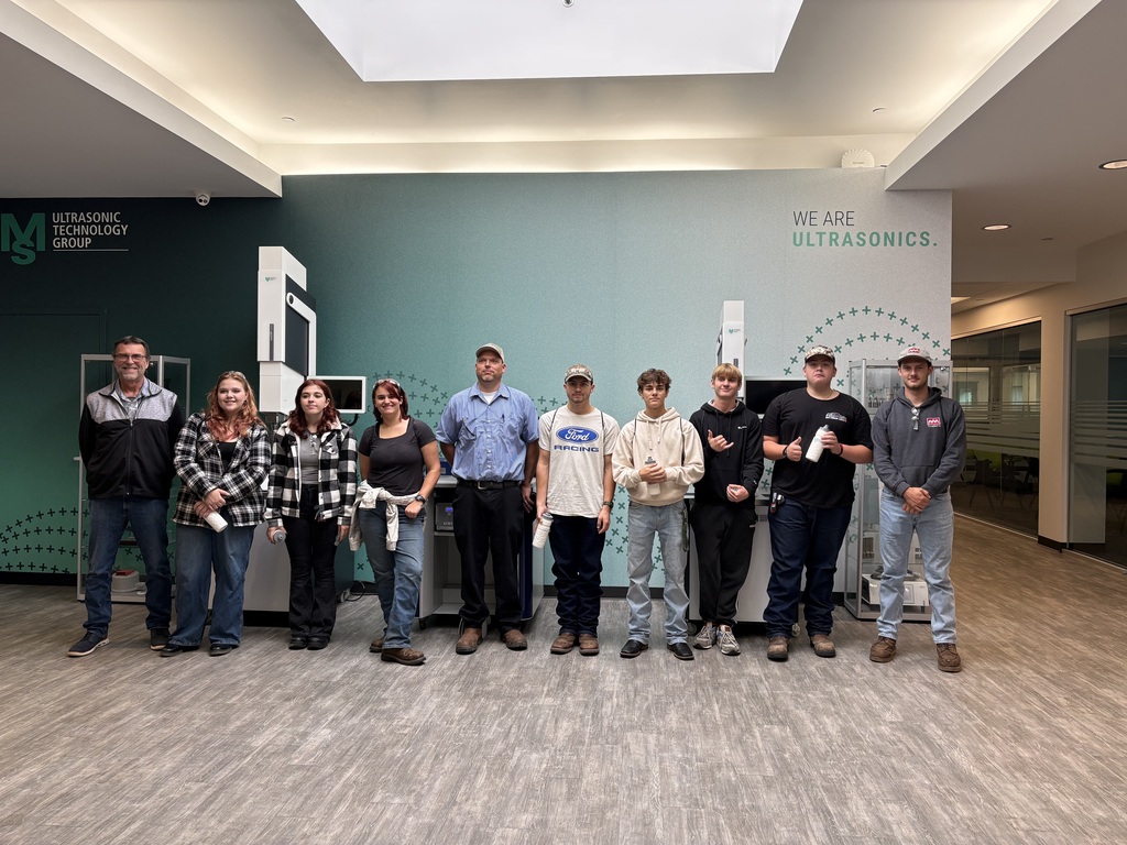 Group of nine people standing together for a photo in the lobby of Ultrasonic Technology Group, with the company logo and “We Are Ultrasonics” branding visible on the wall behind them.