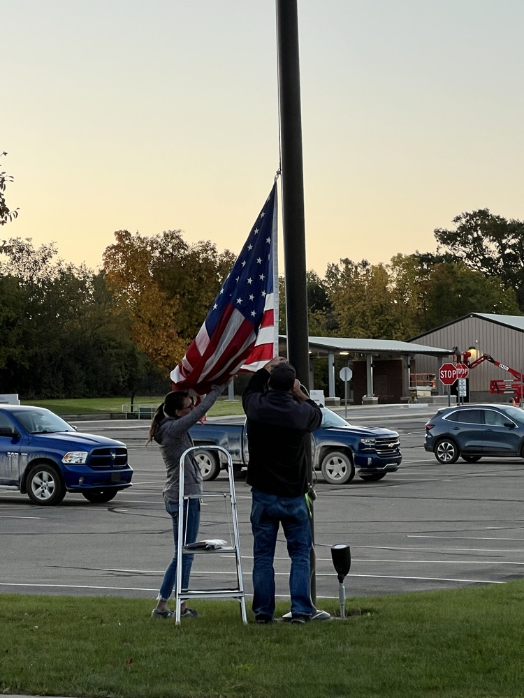Two people taking down an American flag 