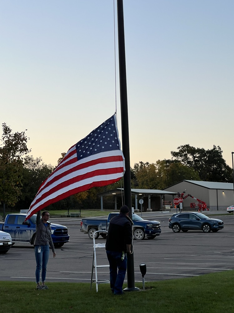 Two people putting up an American flag. 