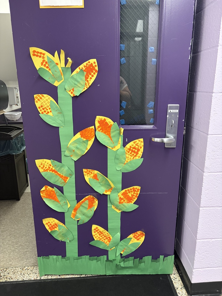 GSRP students’ colorful LEGO-painted corn cobs displayed on a classroom door, with green paper stems and leaves.