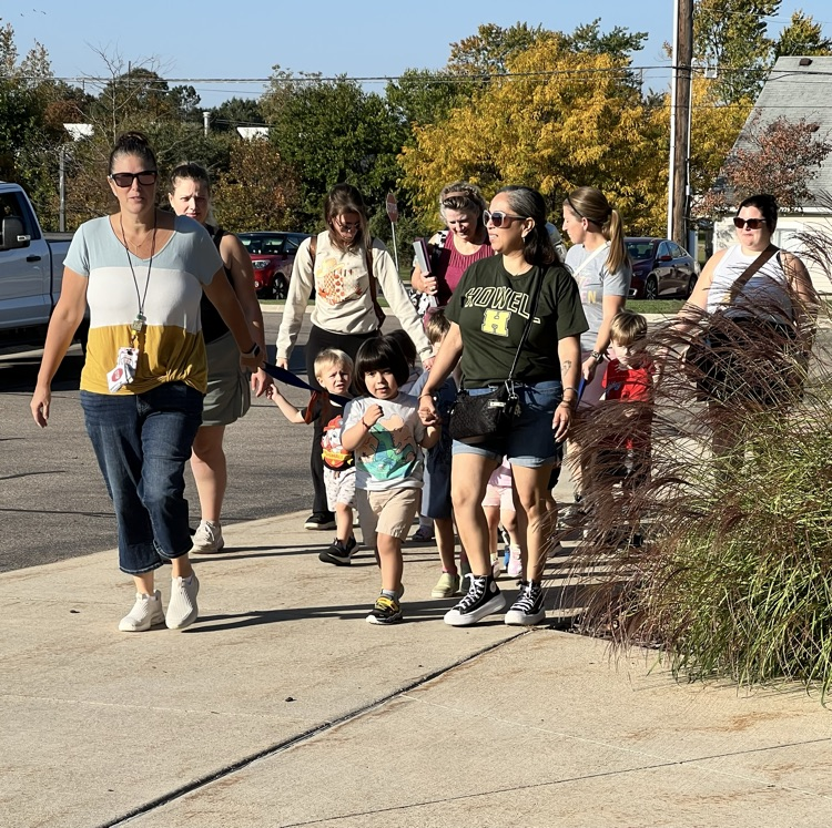Group of adult women walking with small children outside. 