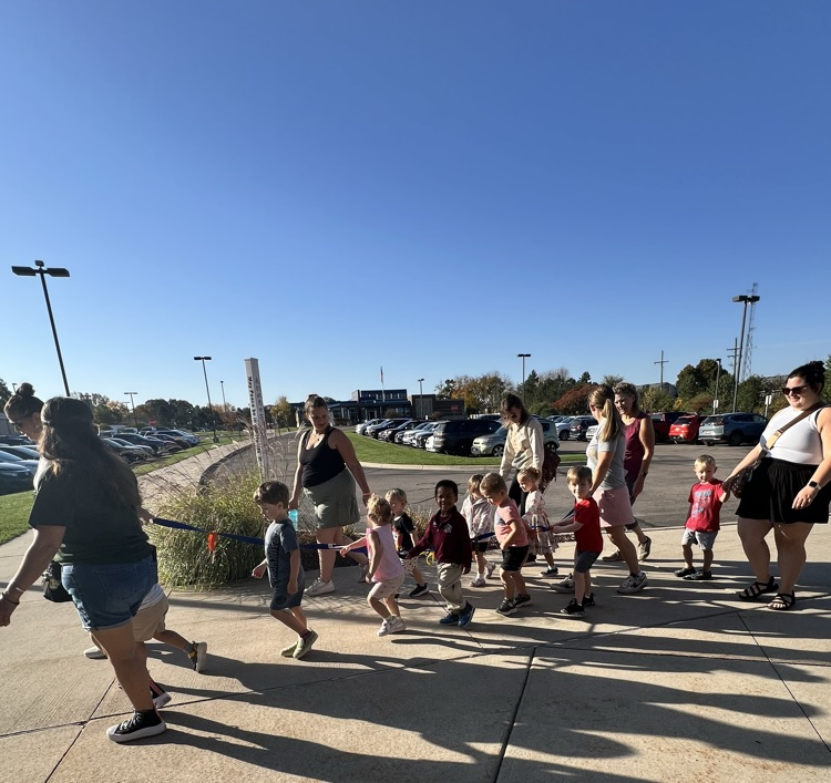 Group of adult women walking with children outside. 