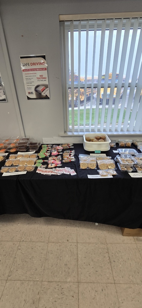 Baked goods individually packaged on a covered table for a bake sale. 