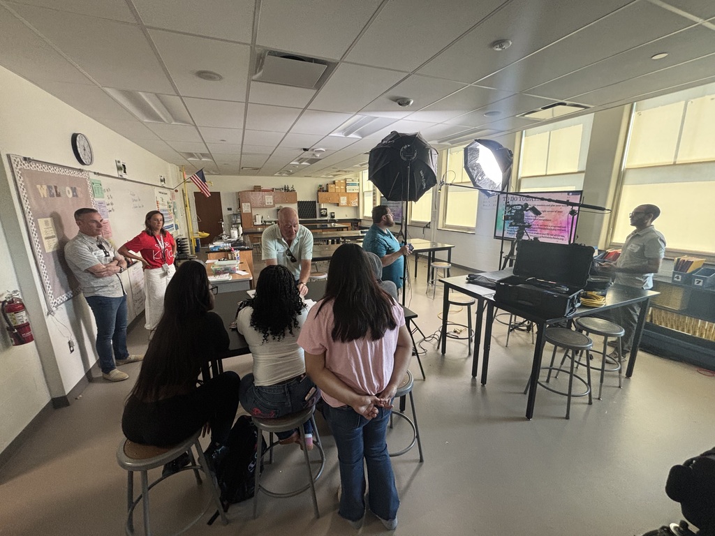 Students working with a video crew to create a promotional video for Adopt A Class