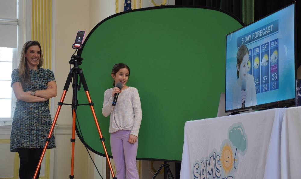 An LVI student works with Samantha Augeri, an Emmy Award-winning meteorologist, to practice her own broadcast.