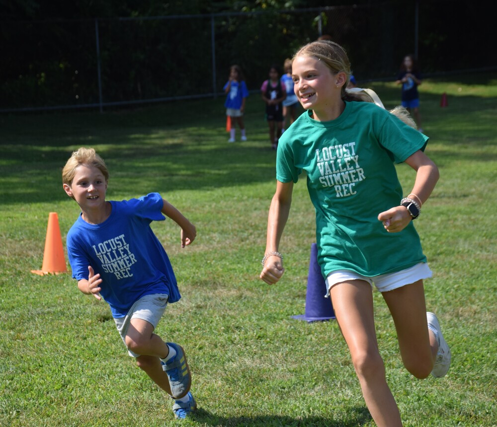 A summer recreation camper and counselor run around on field day.