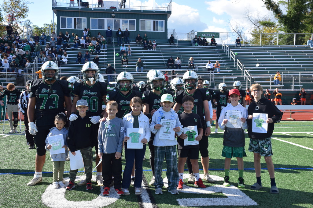 The jersey contest winners walk out onto the field with the captains for the coin toss.