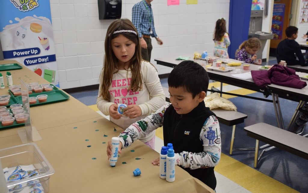 A Bayville Primary school second grader helps a kindergartener vote for strawberry banana.