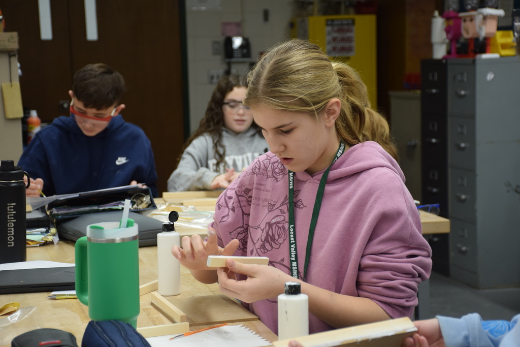 A MS student sands down a piece of wood.
