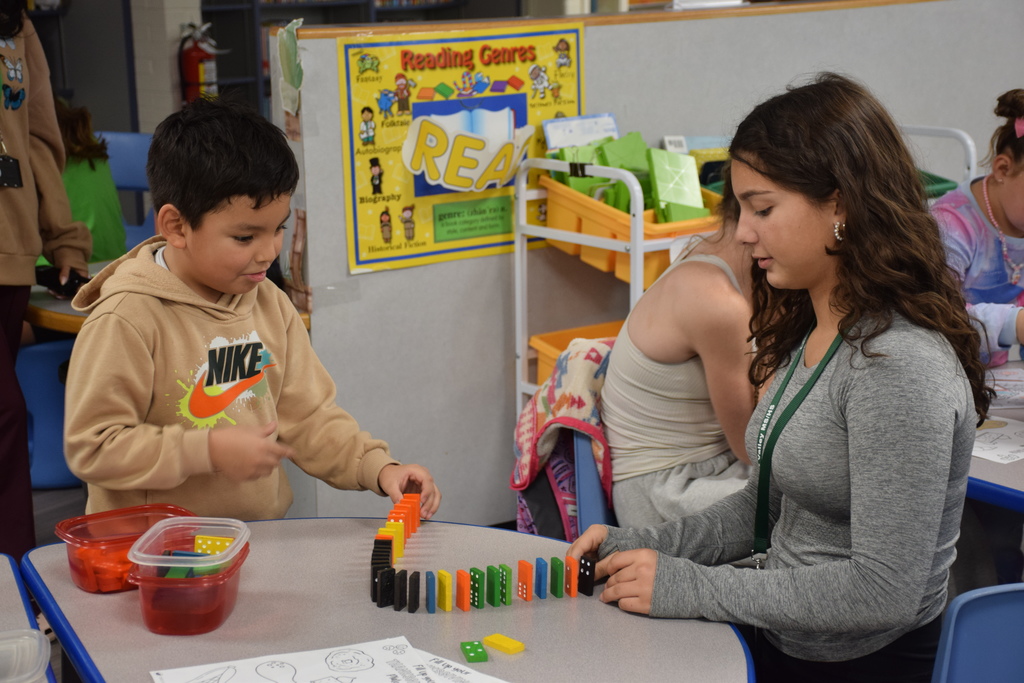 A Bayville Primary student plays dominos with a middle school cheerleader.