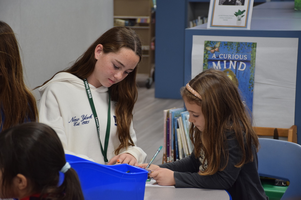 A middle school cheerleader works with a BP student on her homework.