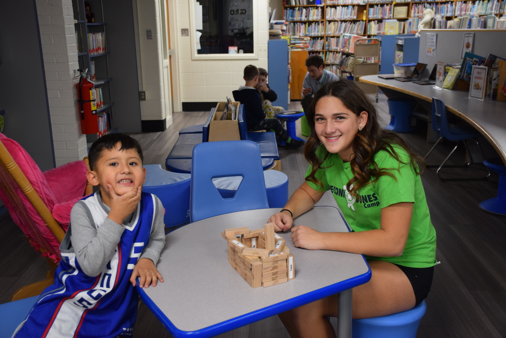A BP student and middle school cheer squad member build with wooden blocks.