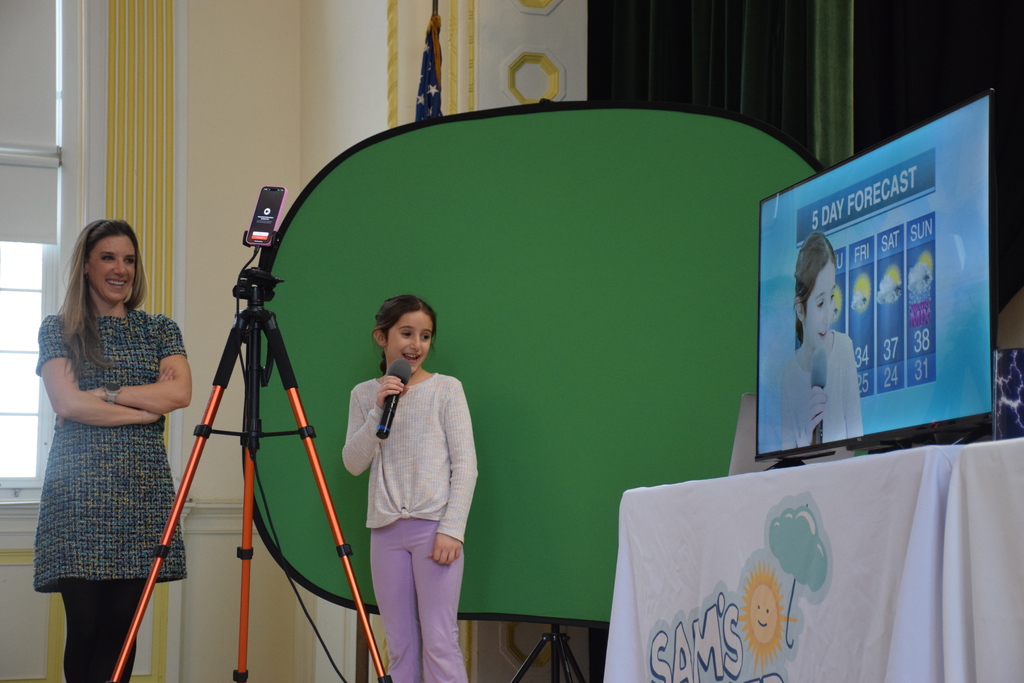An LVI student works with Samantha Augeri, an Emmy Award-winning meteorologist, to practice her own broadcast.