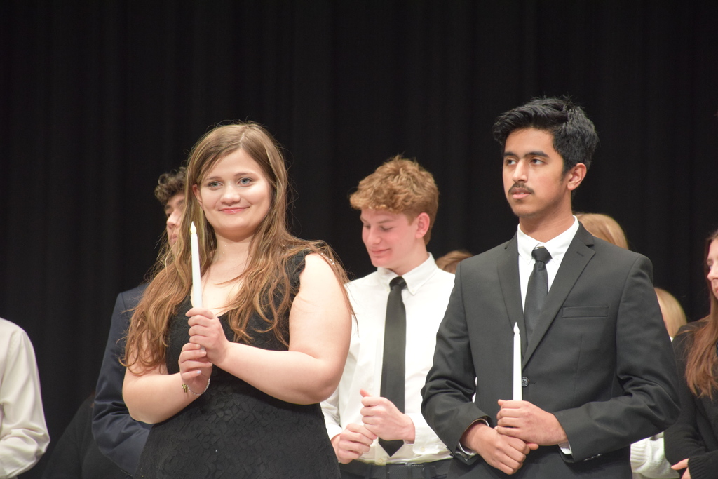 NHS inductees hold up candles representing the values of NHS.