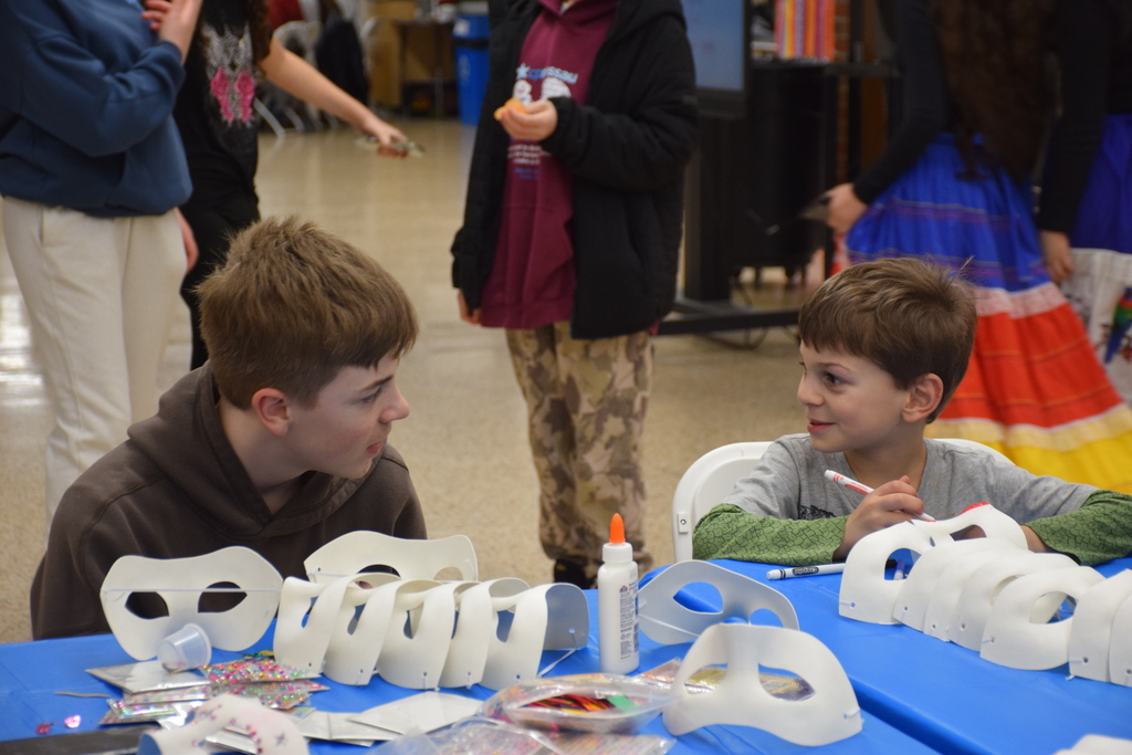 A middle school student helps a community member with their carnivale mask at LVMS/HS International Night 2026.