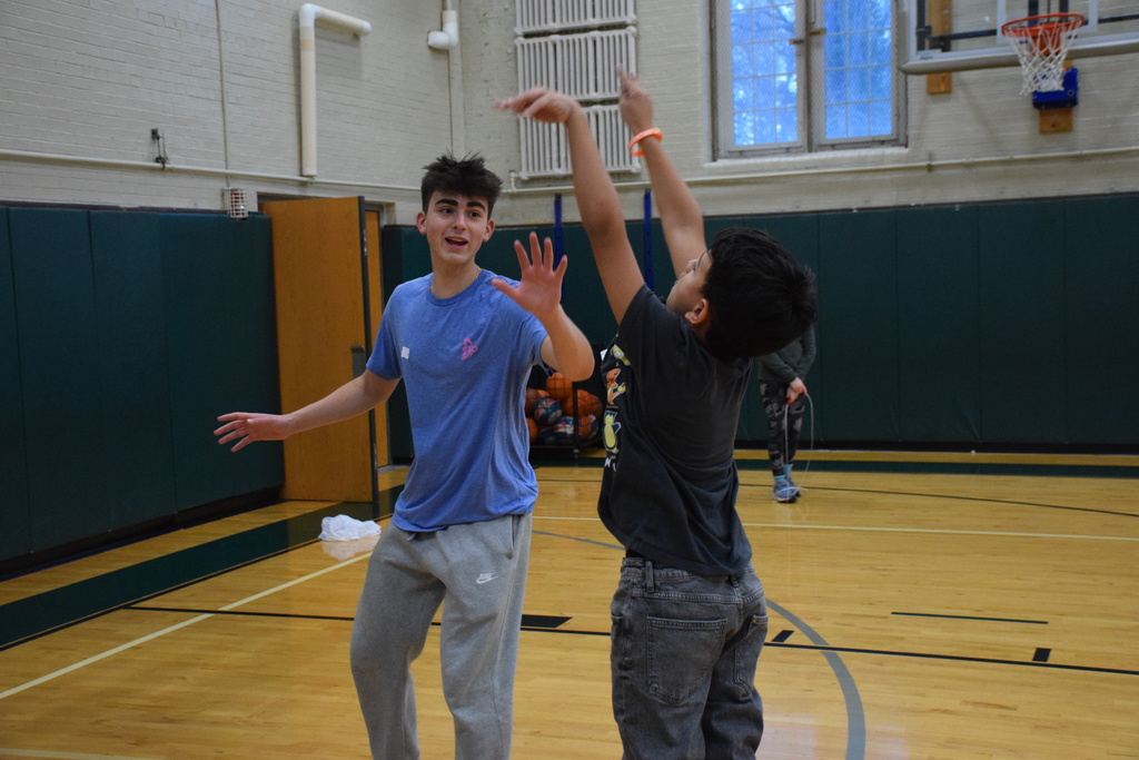 An elementary schooler and high schooler play basketball together on Unplugged Night 2026.