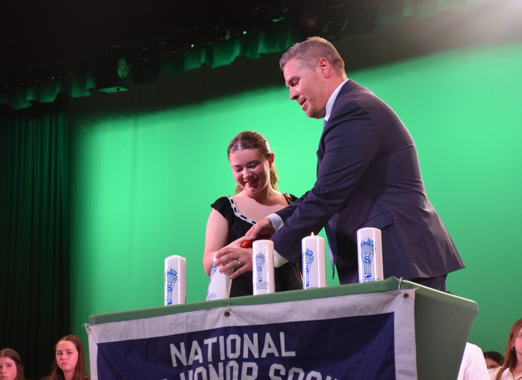 A LVMS student and Principal Cestaro light candles representing the qualities of National Junior Honor Society Members.