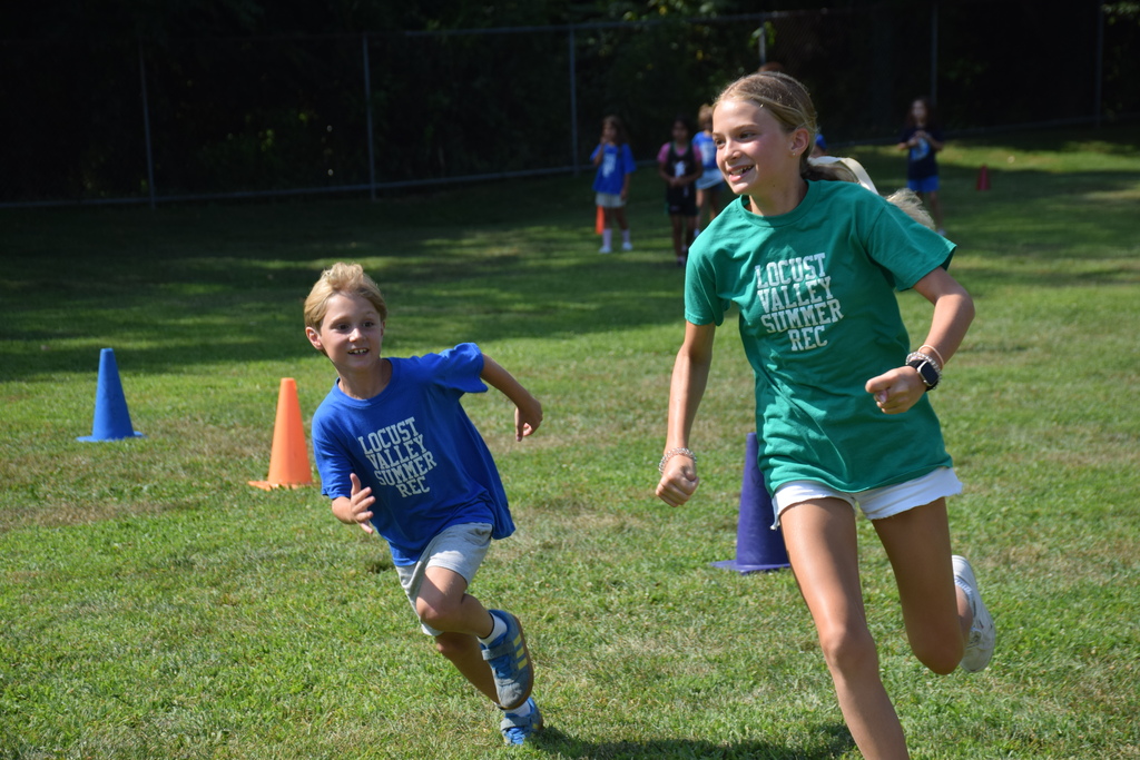 A summer recreation camper and counselor run around on field day. 