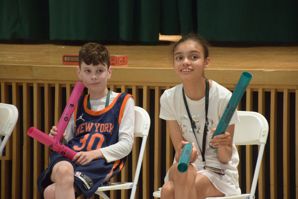 Students play rhythm sticks to the tune of pop songs.