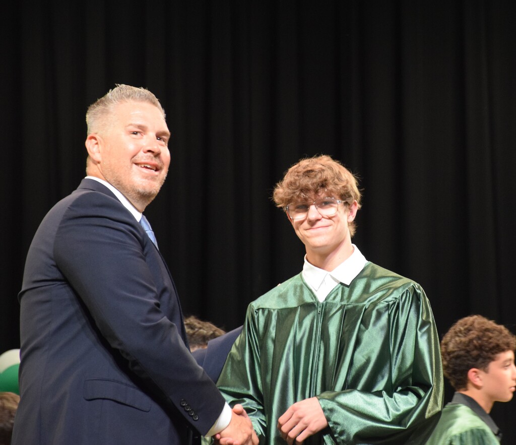 A student accepts his diploma at the eighth grade graduation.