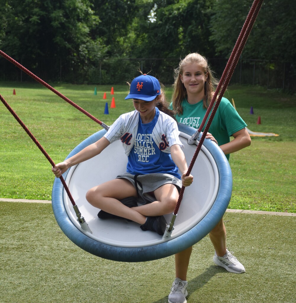 A Summer Recreation counselor pushes a camper on a swing at the Bayville Intermediate School playground.