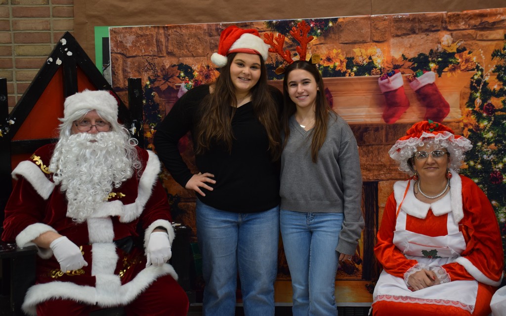 1)	Locust Valley High School seniors Ella Crocco (center left) and Gianna Palleschi (center right) brought in Santa and Mrs. Claus on Dec. 20 to take pictures with students who donated food for their International Baccalaureate project. 