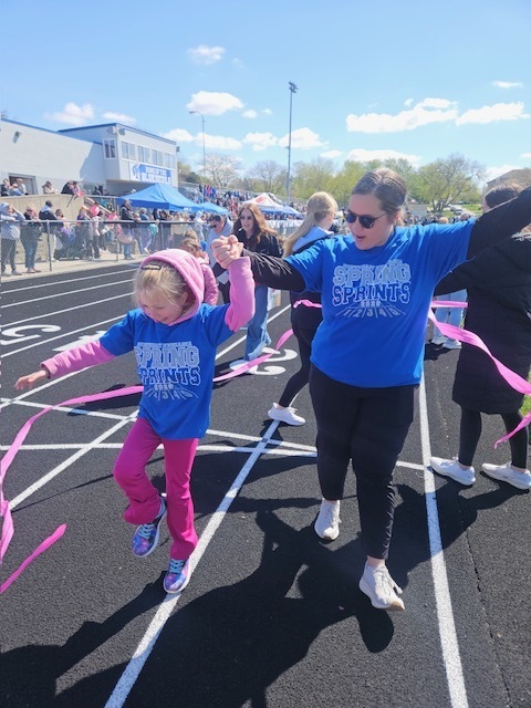 student and helper crossing finish line