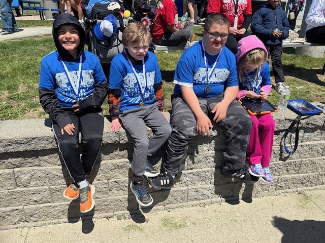 students sitting outside smiling with medals