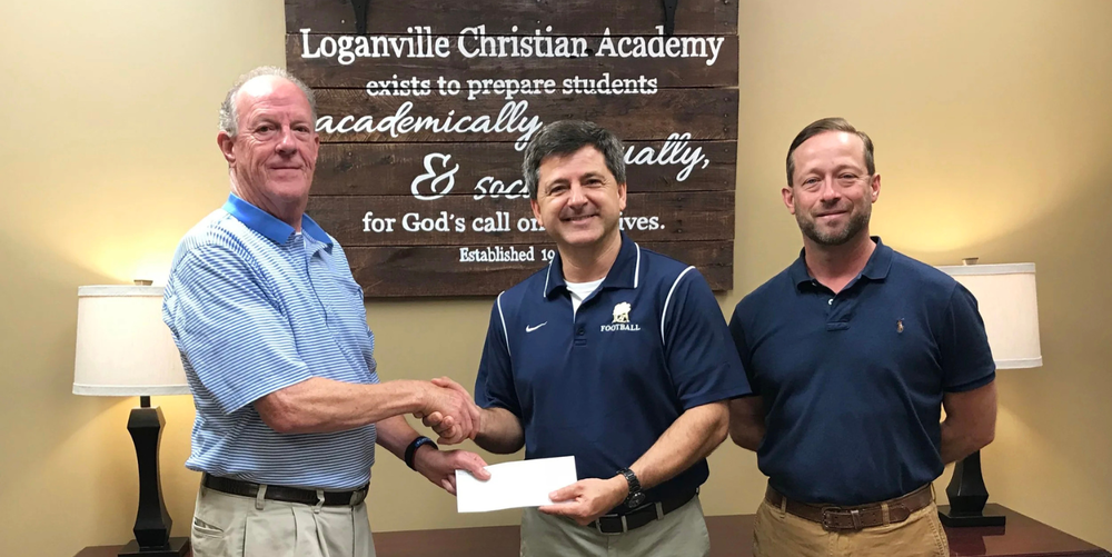 Three men pose for a photo smiling with two on the left shaking hands.
