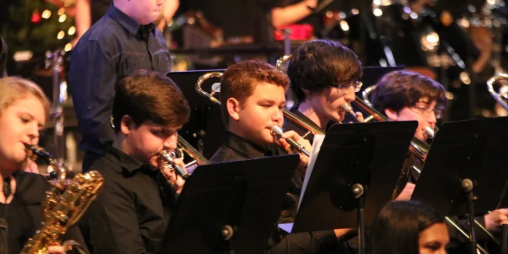 A group of young students wearing all black play golden instruments 