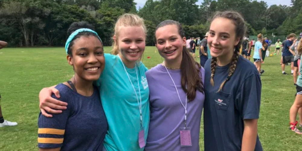 A group of four students pose for a photo outside while participating in outdoor activities.